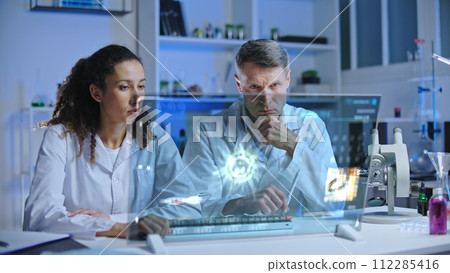 Laboratory scientists looking at infected cell mutation, discussing experiment results Laboratory scientists looking at infected cell mutation, discussing experiment results 112285416