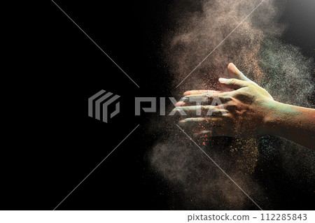 Closeup of hand holding colorful holi powder isolated over black background. 112285843