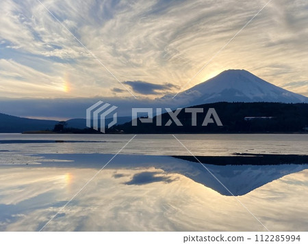 Evening view of Lake Yamanaka, inverted Mt. Fuji, frozen ice, and phantom sun 1 112285994