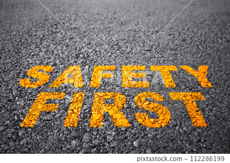 Safety first with yellow sign on asphalt road, warning concept of industrial attention for employee awareness. Safety first with yellow sign on asphalt road, warning concept of industrial attention for employee awareness. 112286199
