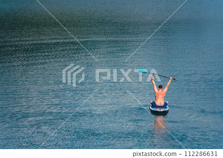 man on paddleboard in the middle of the lake man on paddleboard in the middle of the lake 112286631