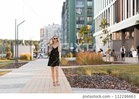 Young woman walking on city streets with while talking on her phone Young woman walking on city streets with while talking on her phone 112286663
