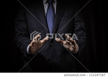 Businessman gesturing hand out on black background Businessman gesturing hand out on black background 112287167