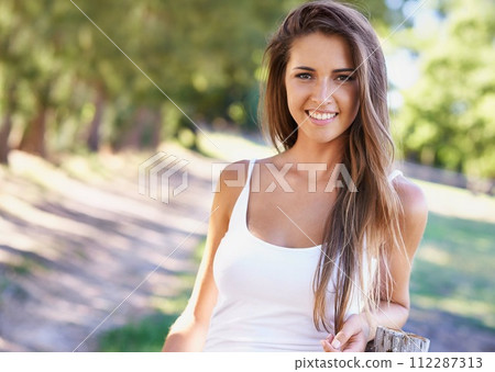 Portrait, woman or smile for hair, fashion or summer in casual outfit with natural styling in park. Happy, female person and vest in sunlight for stylish, trendy and clothing in woods in Portugal 112287313