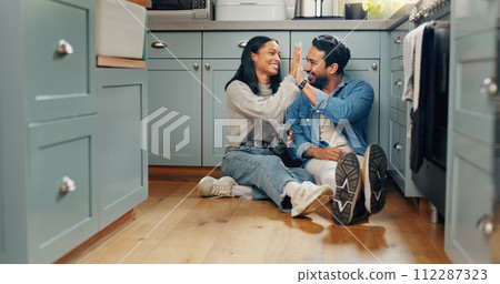 Couple, coffee and sitting on floor in kitchen for quality time or fun to celebrate or discussion. Love, smile and woman with high five are bonding together with caffeine and conversation or care. Couple, coffee and sitting on floor in kitchen for quality time or fun to celebrate or discussion. Love, smile and woman with high five are bonding together with caffeine and conversation or care. 112287323