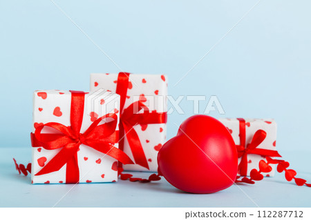 gift box with red bow and red heart on colored background. Perspective view. Flat lay gift box with red bow and red heart on colored background. Perspective view. Flat lay 112287712