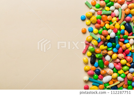 Mixed collection of colorful candy, on colored background. Flat lay, top view. frame of colorful chocolate coated candy 112287751