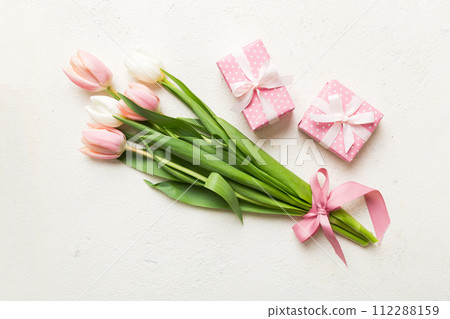 Pink tulips flowers and gift or present box on colored table background. Mothers Day, Birthday, Womens Day, celebration concept. Space for text top view 112288159