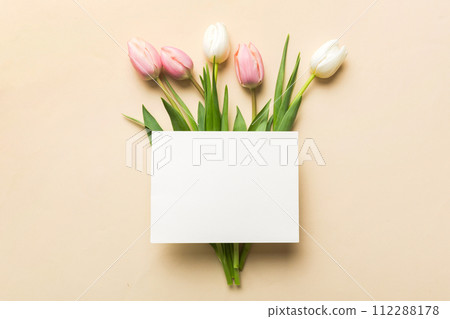 Composition with blank card and beautiful flowers tulip on coloredbackground. top view with space for you desing 112288178
