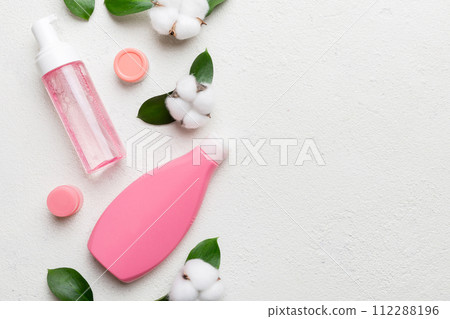 Organic cosmetic products with cotton flower and green leaves on cement background. Copy space, flat lay Organic cosmetic products with cotton flower and green leaves on cement background. Copy space, flat lay 112288196