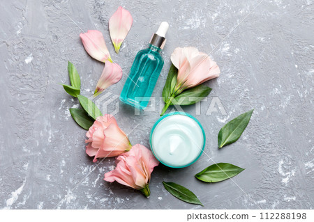 Composition with cosmetic products and beautiful roses on cement background. Flat lay Composition with cosmetic products and beautiful roses on cement background. Flat lay 112288198
