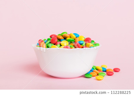 Multicolored candies in a bowl on a colored background. birthday and holiday concept. Top view with copy space Multicolored candies in a bowl on a colored background. birthday and holiday concept. Top view with copy space 112288225