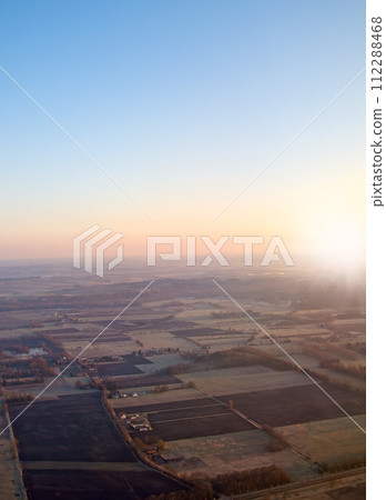 Town, aerial view and countryside in outdoors at sunset, field and sustainable environment on travel. Blue sky, peace and mockup space in nature, drone and town for ecosystem at dusk or landscape 112288468