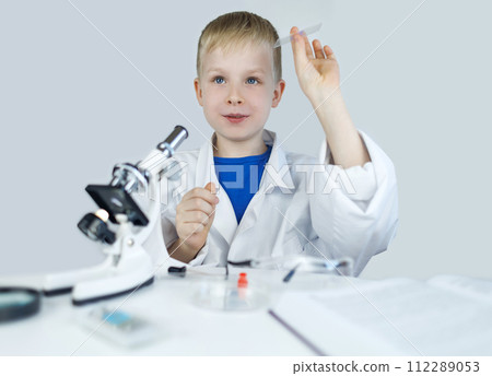 Child chemist. Teacher shows a visual experiment. A science mentor teaches an experimental approach. Microscope, petri dish, pipettes, books. Practical work in chemistry or physics. Laboratory work 112289053