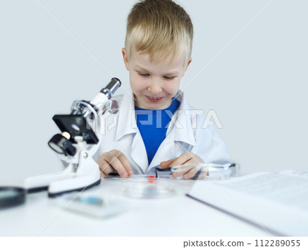 Child chemist. Teacher shows a visual experiment. A science mentor teaches an experimental approach. Microscope, petri dish, pipettes, books. Practical work in chemistry or physics. Laboratory work 112289055