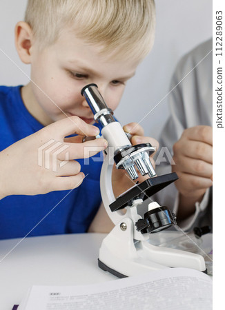Child chemist. Teacher shows a visual experiment. A science mentor teaches an experimental approach. Microscope, petri dish, pipettes, books. Practical work in chemistry or physics. Laboratory work Child chemist. Teacher shows a visual experiment. A science mentor teaches an experimental approach. Microscope, petri dish, pipettes, books. Practical work in chemistry or physics. Laboratory work 112289063