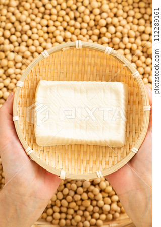 A woman holds handmade firm tofu in a colander A woman holds handmade firm tofu in a colander 112289161