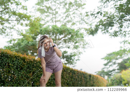 Asian woman taking a moment to catch her breath after tired workout in park Asian woman taking a moment to catch her breath after tired workout in park 112289966