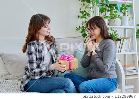 Teenage daughter congratulating middle aged mother with gift Teenage daughter congratulating middle aged mother with gift 112289967