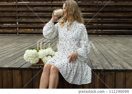Girl with flowers and coffee, on the street in summer. Girl with flowers and coffee, on the street in summer. 112290099