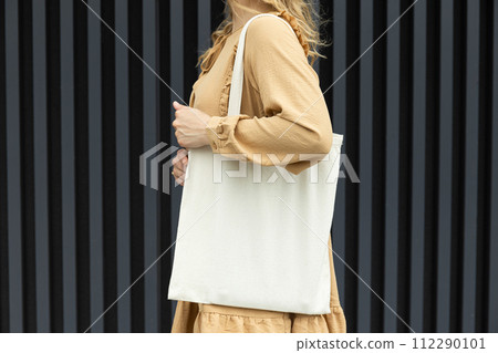A girl in a summer outfit with a reusable shopping bag. 112290101