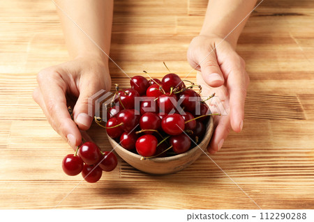 Ripe cherry fruits in a bowl on a wooden background Ripe cherry fruits in a bowl on a wooden background 112290288