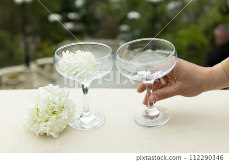Two glass glasses with flowers on the background of the sea. Two glass glasses with flowers on the background of the sea. 112290346