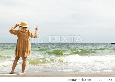 A girl in a dress walks on the beach in the summer. A girl in a dress walks on the beach in the summer. 112290433