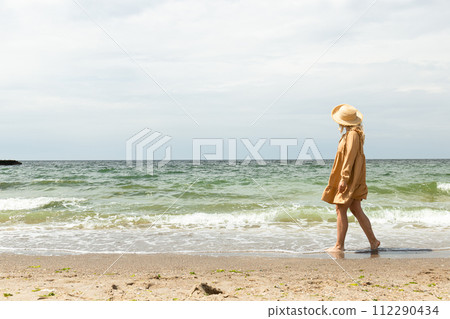A girl in a dress walks on the beach in the summer. A girl in a dress walks on the beach in the summer. 112290434