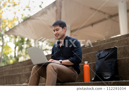 Asian businessman with reusable eco friendly ecological cup using laptop and sitting outside the office building. Eco friendly, sustainable lifestyle concept Asian businessman with reusable eco friendly ecological cup using laptop and sitting outside the office building. Eco friendly, sustainable lifestyle concept 112291034