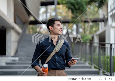 Smiling asian businessman walking to work while to hold reusable eco friendly ecological cup in the city Smiling asian businessman walking to work while to hold reusable eco friendly ecological cup in the city 112291035
