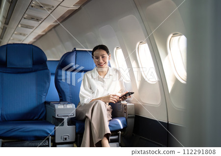 Traveling and technology. Flying at first class. Young business woman passenger using smartphone while sitting in airplane flight 112291808