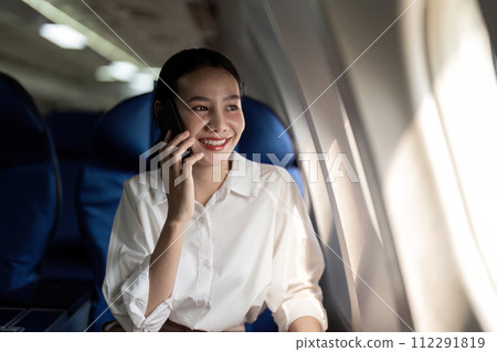 Traveling and technology. Flying at first class. Young business woman passenger using smartphone while sitting in airplane flight 112291819