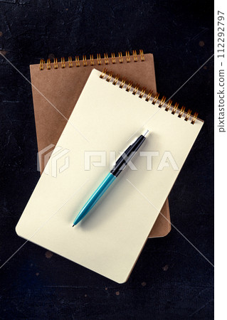 Notebook mockup with a pen, top shot on black 112292797