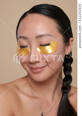Portrait of smiling young woman with hydrogel undereye patches Portrait of smiling young woman with hydrogel undereye patches 112292850