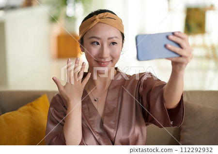 Happy Chinese woman showing manicure she made when taking selfie 112292932