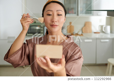 Portrait of Chinese young woman applying powder blush on cheeks Portrait of Chinese young woman applying powder blush on cheeks 112292966