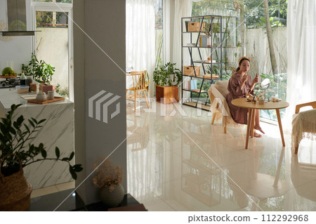 Young woman in silk robe doing makeup in the morning 112292968