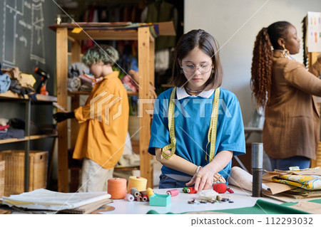 Waist up portrait of young girl with disability sorting threads by color in sewing class copy space Waist up portrait of young girl with disability sorting threads by color in sewing class copy space 112293032