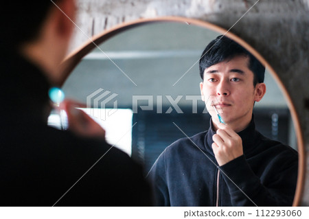 A man brushing his teeth in front of the mirror at the sink 112293060