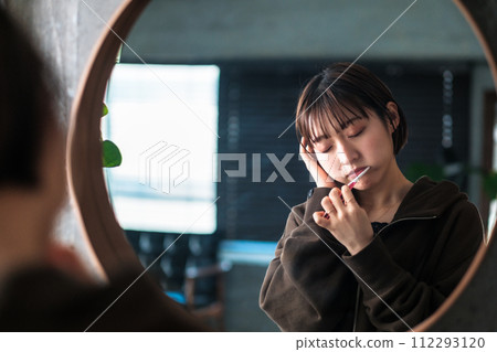 一位女士早上在浴室鏡子前刷牙 112293120