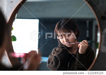 一位女士早上在浴室鏡子前刷牙 112293125