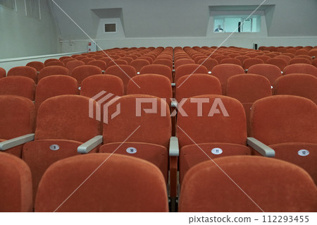 Empty cinema hall with orange seats with copy space. Seats with numbers in theatre. Empty cinema hall with orange seats with copy space. Seats with numbers in theatre. 112293455