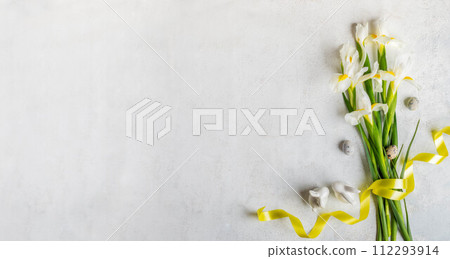 Bouquet of white Iris flowers, yellow ribbon, quail eggs, small ceramic bunnies on white Copy space Bouquet of white Iris flowers, yellow ribbon, quail eggs, small ceramic bunnies on white Copy space 112293914