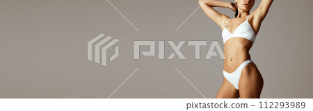 Banner. Slim and perfect female model posing in lingerie against grey studio background with negative space to insert text. 112293989