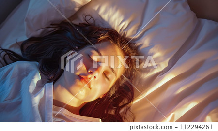 Stylish Sleeping Woman in Bed Under Soft Light Stylish Sleeping Woman in Bed Under Soft Light 112294261