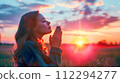 Woman in Field at Sunset Praying with Faith and Hope 112294277