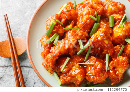 Gobi Manchurian is a crispy fried cauliflower made with chiles, garlic, and ginger sauce closeup on the plate. Horizontal top view Gobi Manchurian is a crispy fried cauliflower made with chiles, garlic, and ginger sauce closeup on the plate. Horizontal top view 112294770