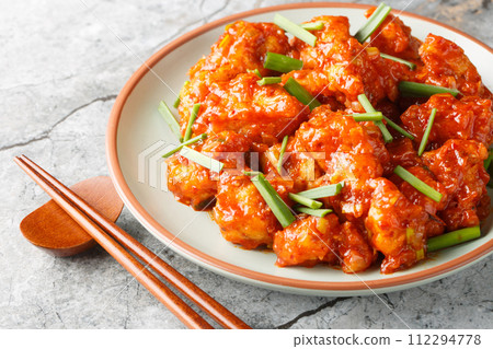 Gobi manchurian is a traditional Indo Chinese dish consisting of fried cauliflower tossed in a sweet and spicy sauce closeup on the plate. Horizontal 112294778