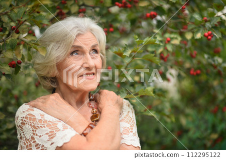 Portrait of happy senior woman posing at forest 112295122